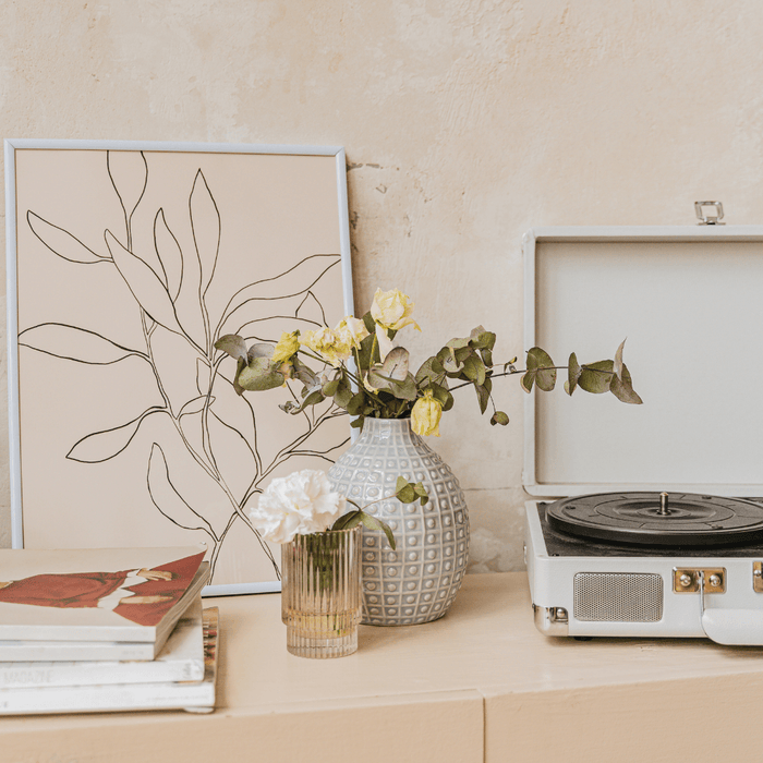 Modern minimalist decor with a vintage record player, floral vase, and stylish wall art.