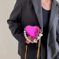 Woman holding LushHoming Mini Love-Shape Pearls Handbag in vibrant pink with playful pearl and gold chain accents, blending cute and functional elements.