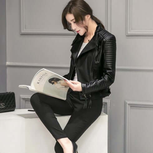 Woman reading in slim black PU leather motorcycle jacket and black pants.