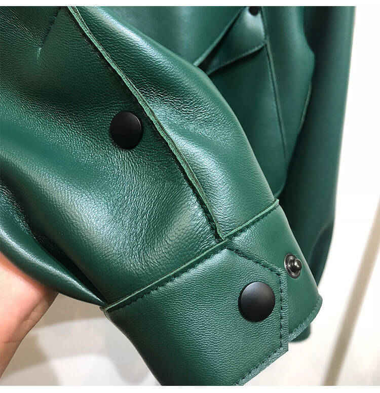 Close-up of green leather sheepskin jacket sleeve with black buttons detailing the high-quality craftsmanship.