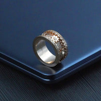 Stylish gold fidget ring for anxiety and focus with rotating band on a sleek laptop surface for stress relief.