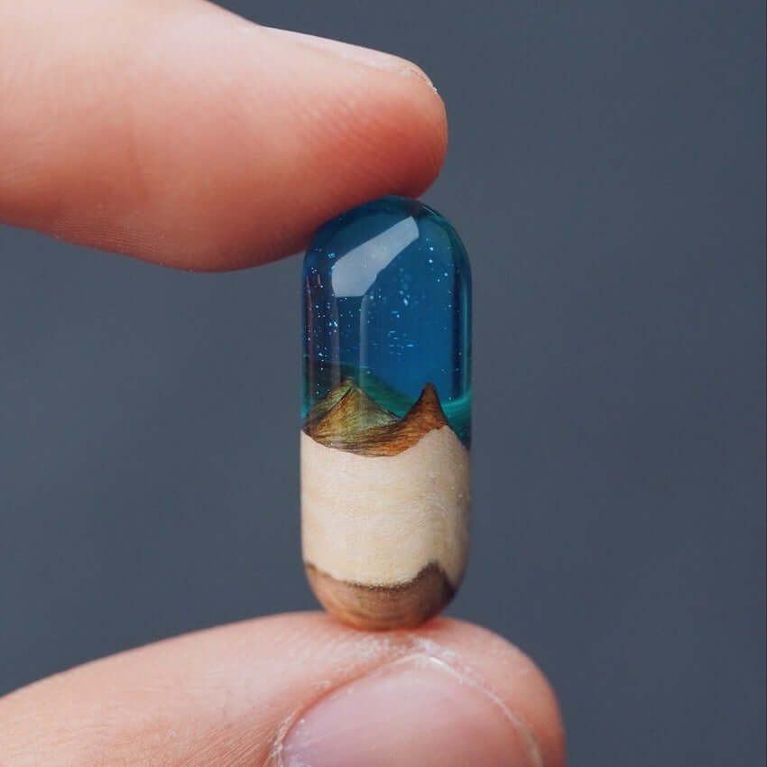 Handcrafted Log Resin Pendant showcasing a real log encased in clear blue resin, held between fingertips against a dark background.