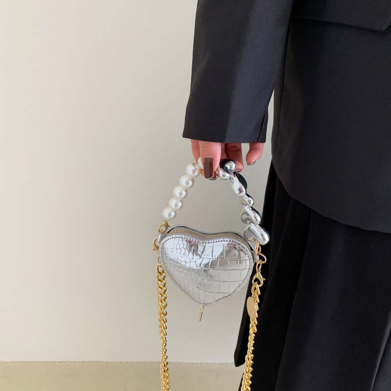 Hand holding Mini Love-Shape Pearls Handbag with a playful heart design, featuring golden chain and pearl details for a cute and functional style.