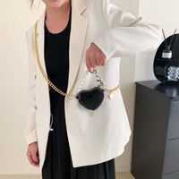 Woman holding Mini Love-Shape Pearls Handbag in black, showcasing playful style and functionality.