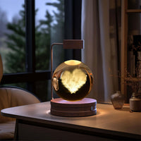 Crystal Ball Cosmic Dinosaur Indoor Night Light USB Power on a desk, warm glow creating a cozy, romantic atmosphere in a bedroom.