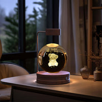 Crystal Ball Cosmic Dinosaur Indoor Night Light on a desk, creating a warm and cozy atmosphere with USB power. Perfect for a bedside light or birthday gift.