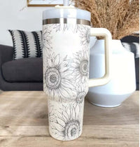 40 oz insulated tumbler with handle and straw in white with sunflowers design on a wooden table in a modern living room setting