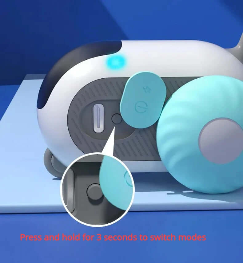 Close-up of a remote control interactive cat car toy showing USB charging port and button with instructions to press and hold to switch modes.